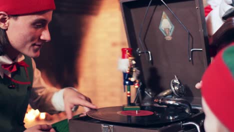 christmas elf playing with a tin toy and a vinyl record on a gramophone. residence of santa claus