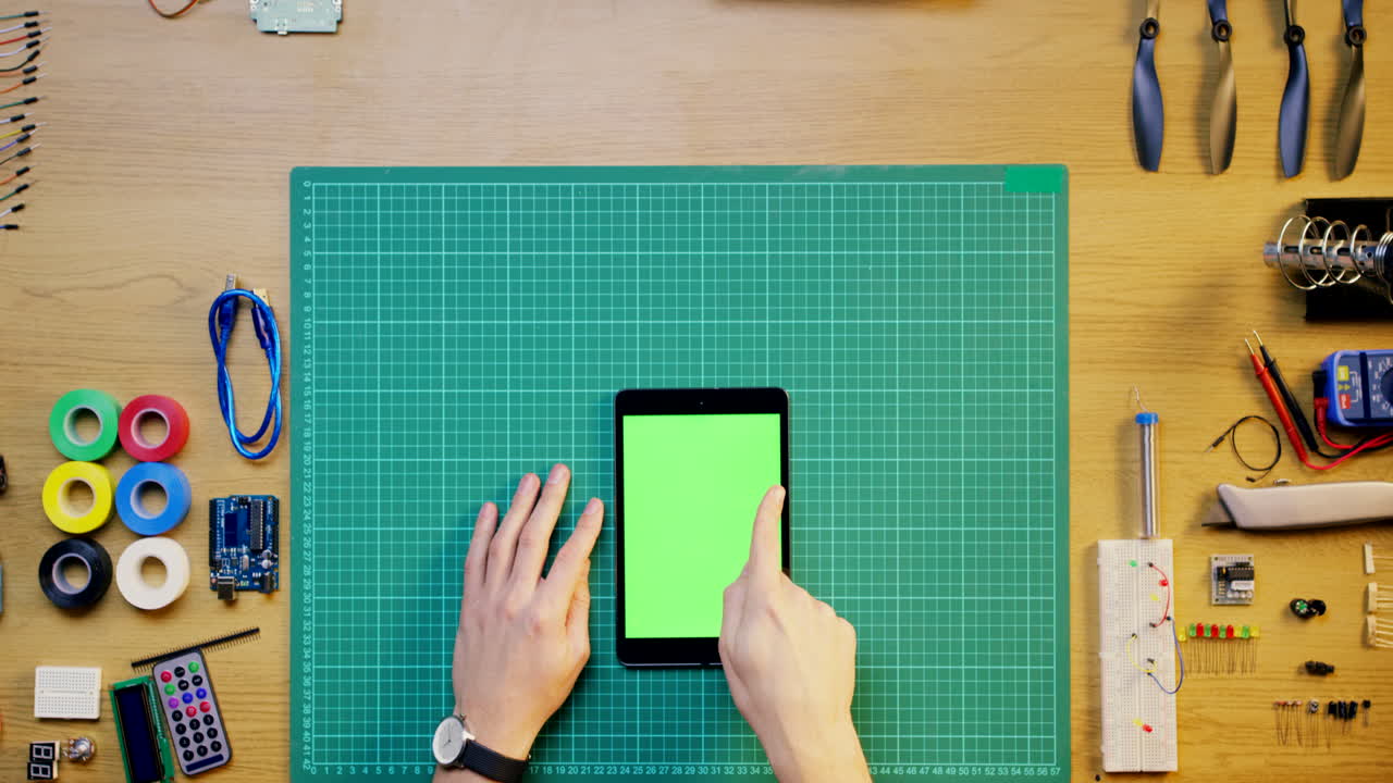 Pessoa Trabalhando em um Projeto de Eletrônica Usando um Tablet com Tela Verde