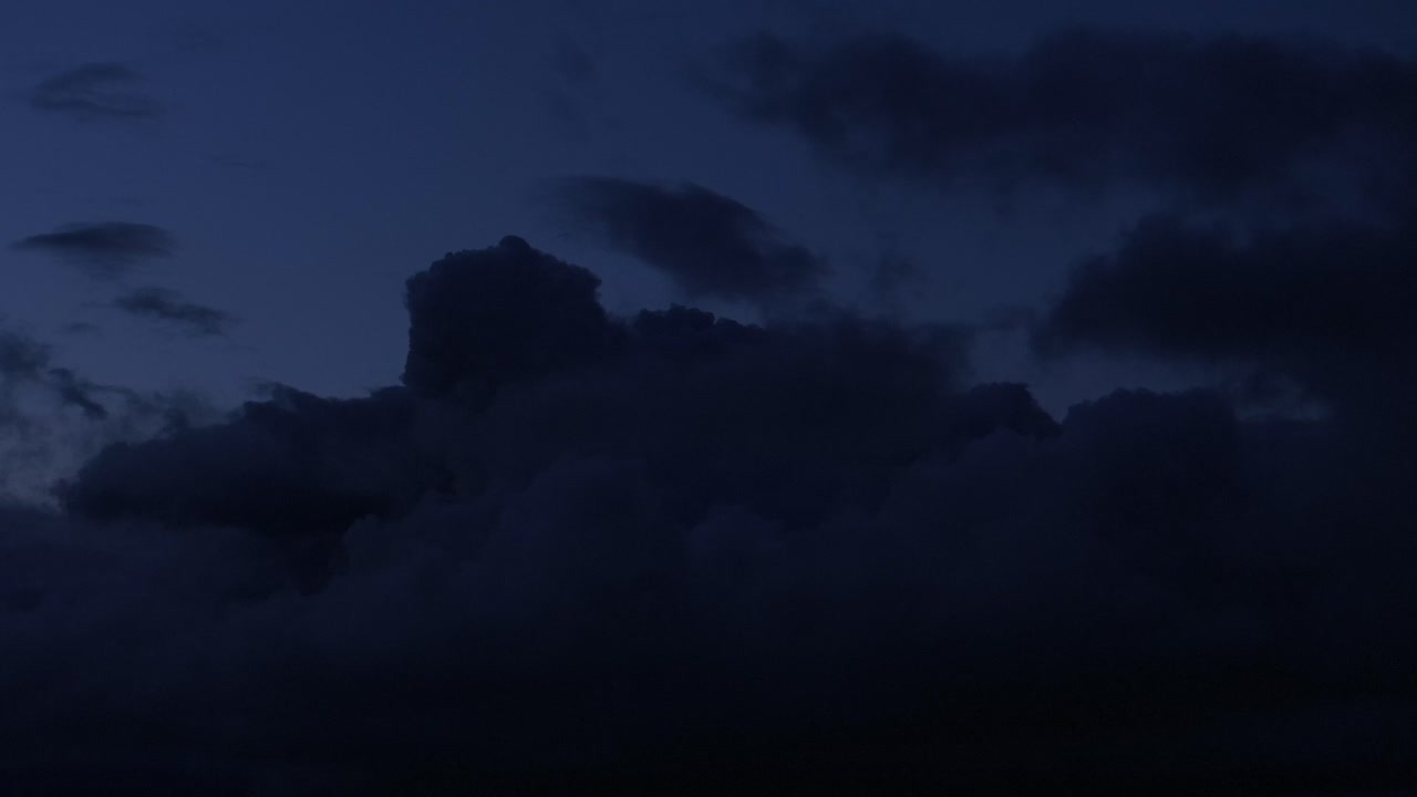 적대적인 침략자처럼 어두운 구름은 파란 스카이라인을 가로질러 조용히 움직입니다.