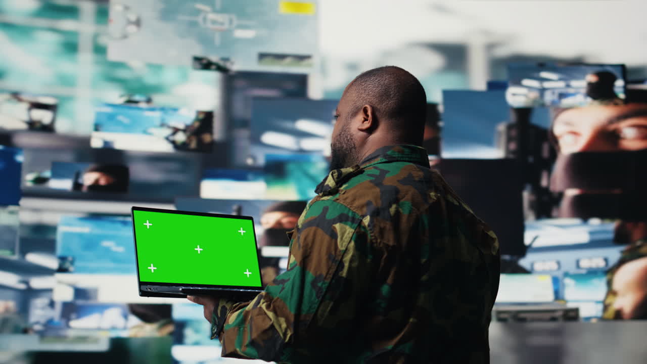 Black army officer reviewing satellite imagery with chroma key on pc
