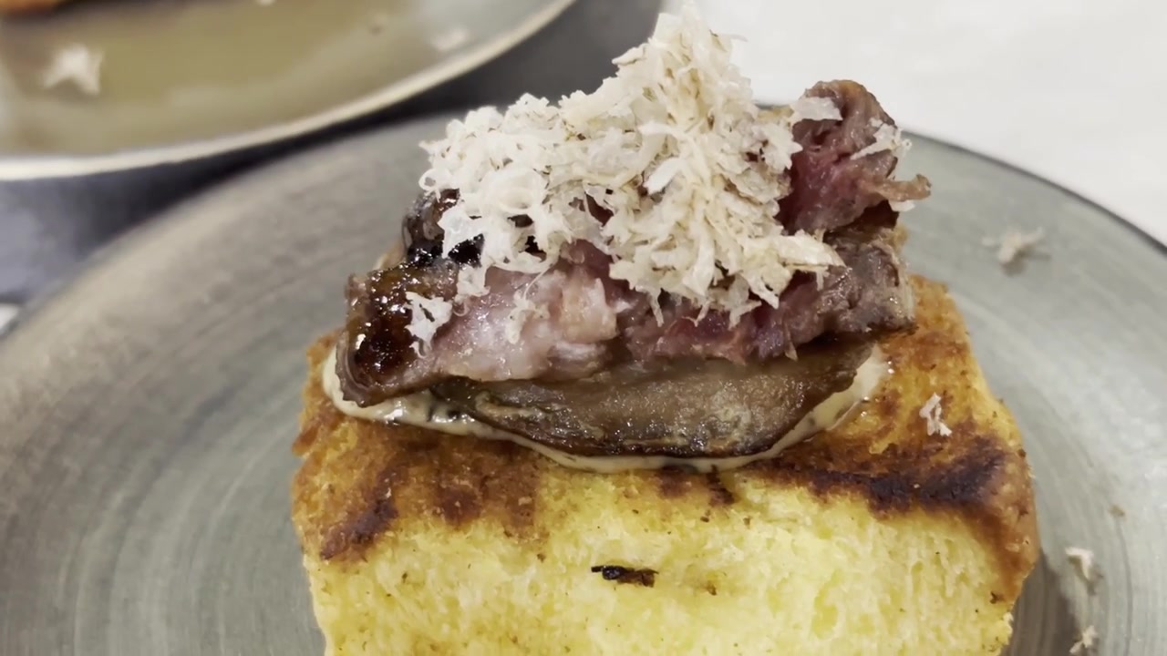 Primer plano de foie gras sellado a la sartén, servido sobre pan tostado y cubierto con láminas de trufa negra, presentado como un lujoso aperitivo gourmet