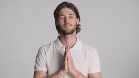 caucasian pleased man in front of camera on gray background.