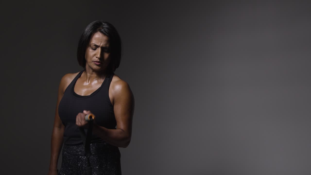 Studio Shot Of Mature Woman Wearing Gym Fitness Clothing Exercising With Resistance Band 2