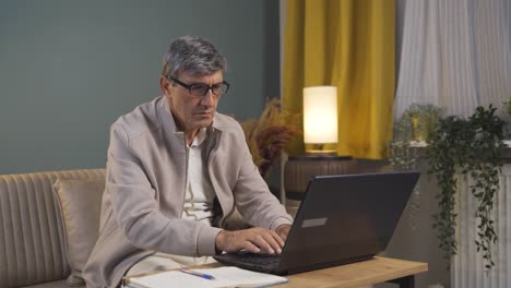 Concentrated old man working on laptop.