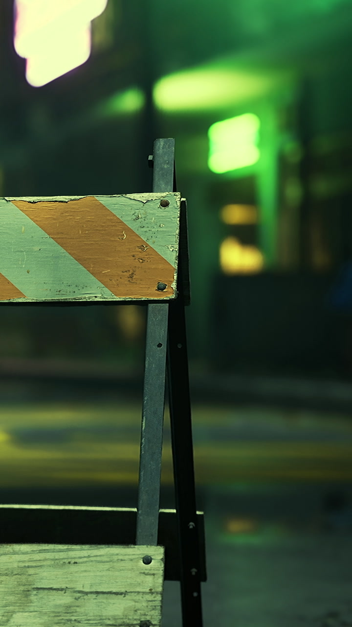 Bright neon lights and construction barriers create an urban evening scene