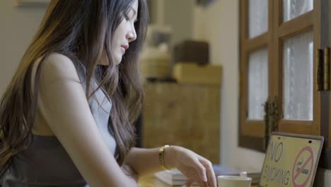 asian women drink hot tea and play phone in cafe.