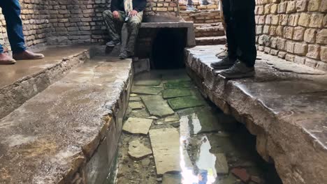 Qanat-El-Canal-De-Agua-Subterráneo-En-El-Desierto-Rural-De-Irán-Para-Transferir-Agua-Dulce-De-La-Montaña-Al-Desierto-De-La-Ciudad-Irrigación-El-Huerto-De-Granados-Y-Pistachos-Agricultura-Tradicional