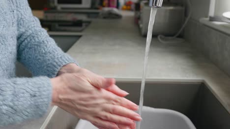 a lady washing her hands at the kitchen sink