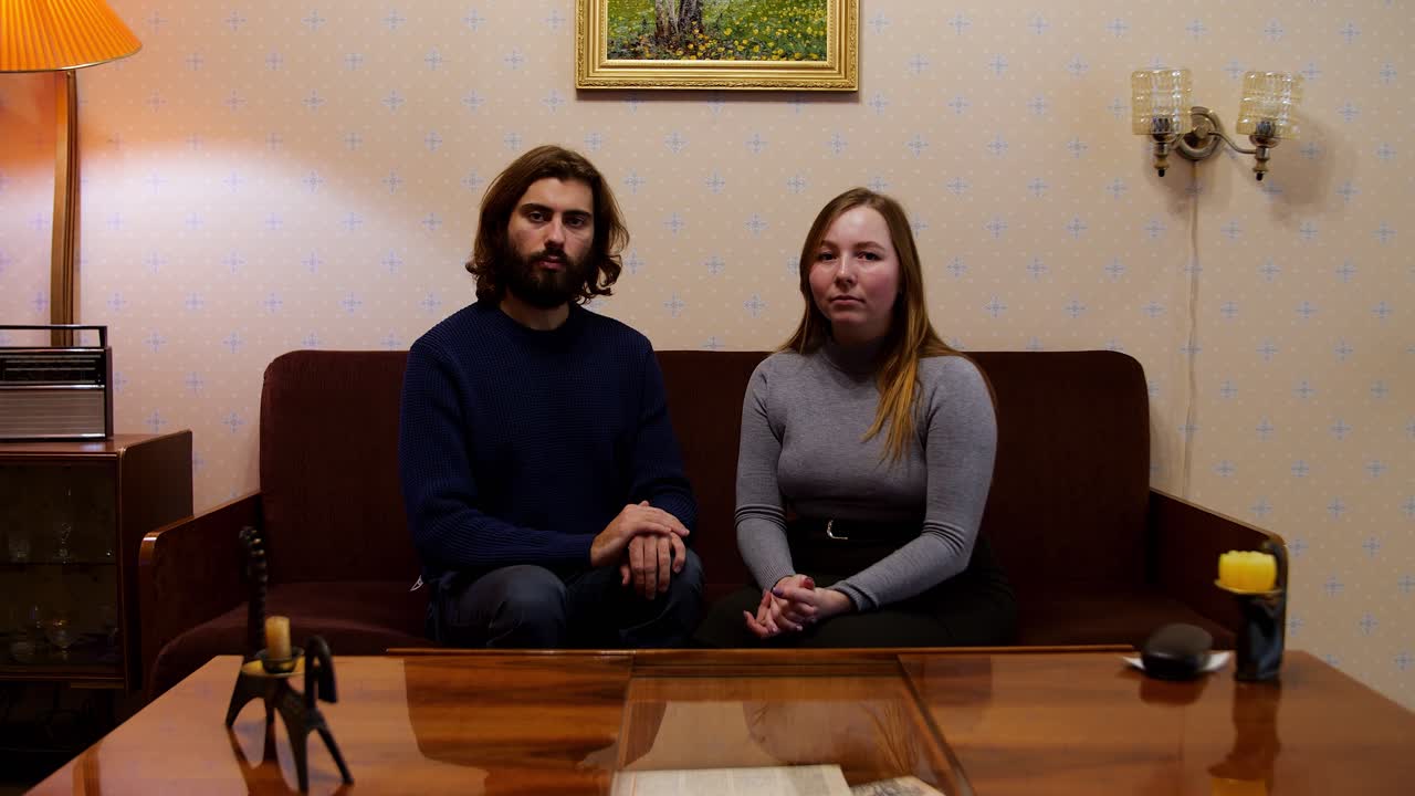 una pareja sentada en el sofá en una sala de estar retro