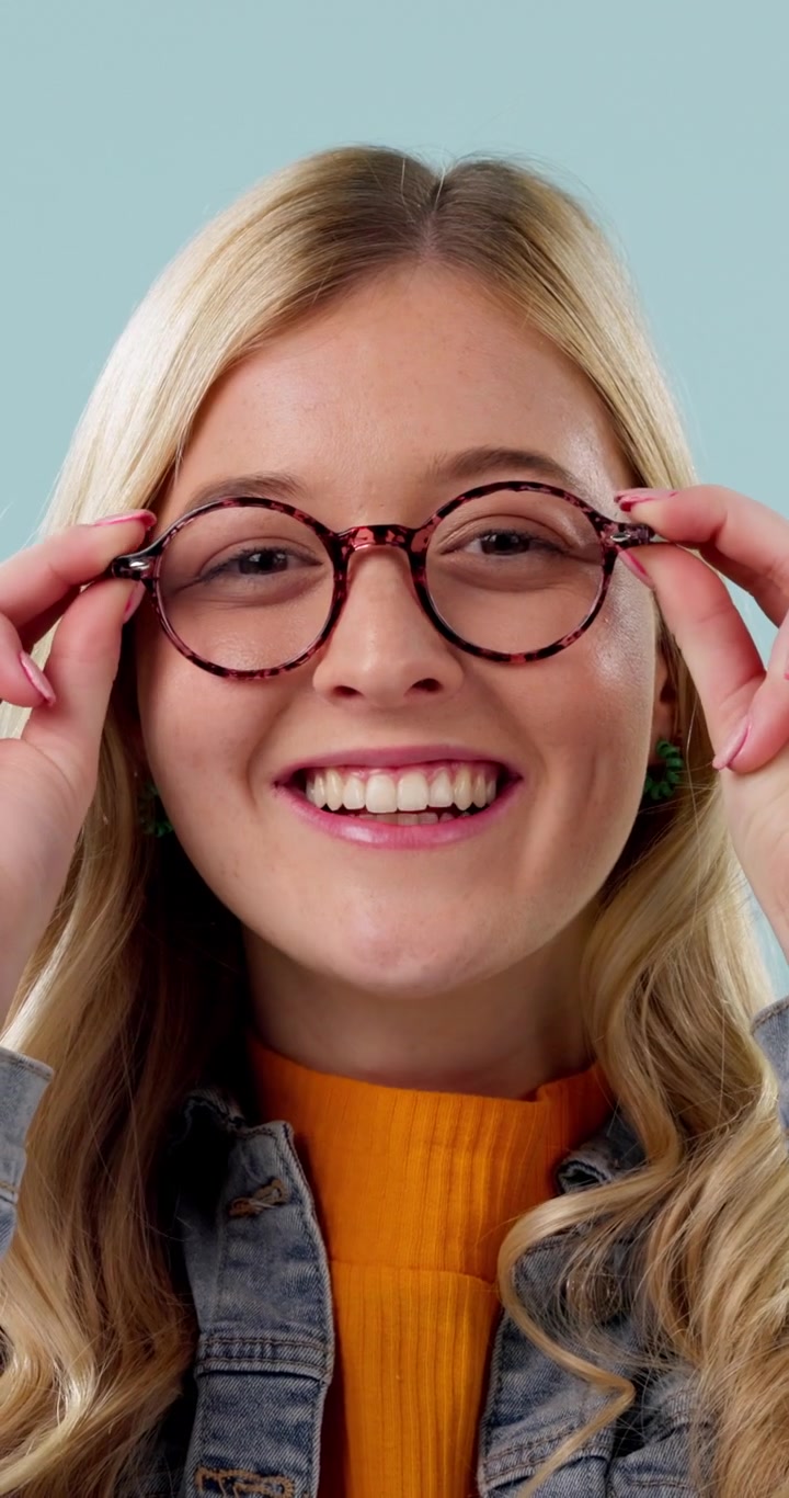 Young Woman Putting On Stylish Tortoiseshell Glasses