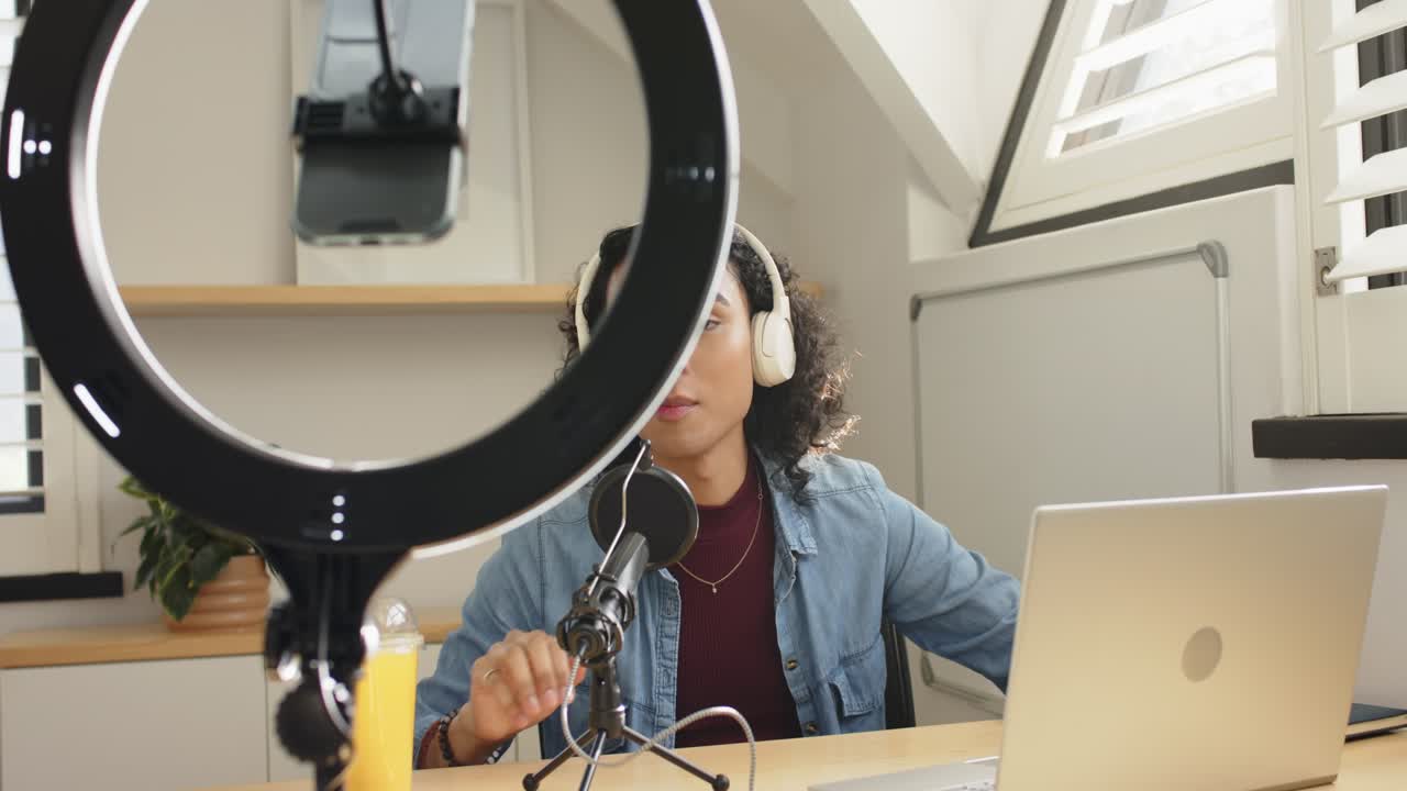 Dopo aver regolato l'asta del microfono, il creatore sta registrando nel microfono, digitando appunti sul portatile sotto una ring light.