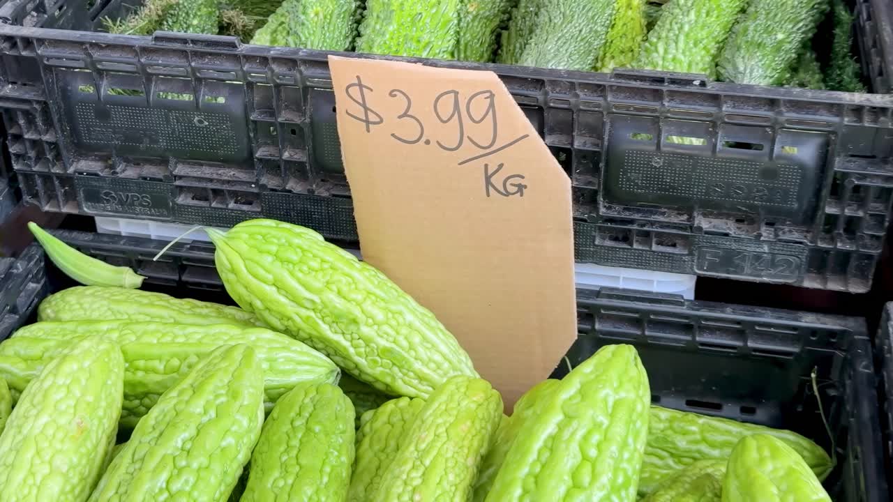 Close-up view of fresh bitter melons priced at $3.99 per kilogram at a market stall.