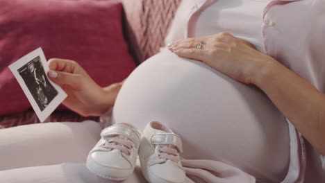 expectant mother rubbing pregnant belly and holding sonogram image