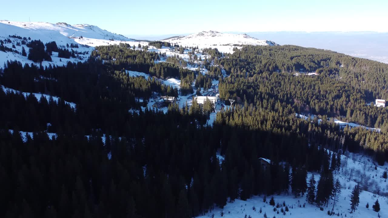 clip aéreo de la estación de esquí de vitosha cerca de sofía, bulgaria con bosques de coníferas y picos cubiertos de nieve en el fondo