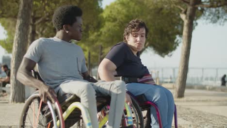 happy young couple dancing using wheelchairs in park