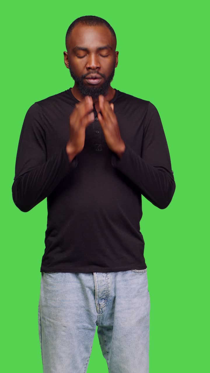 Vertical video: Front view of male person feeling displeased and exhausted in studio