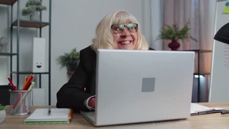 senior mature older business woman hiding behind laptop computer, making funny face, fooling around