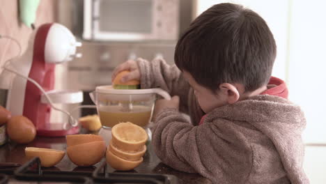 Asian-kid-making-organic-natural-freshly-squeezed-orange-juice-by-himself