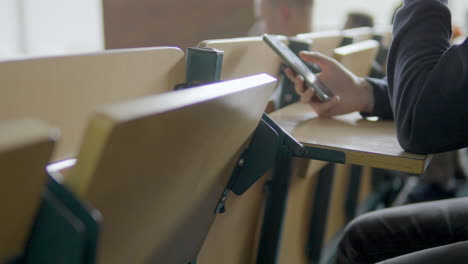 undergrad student in college class distracted by social media on smartphone