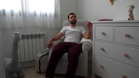 future dad resting in baby room, sitting in chair during late pregnancy weeks