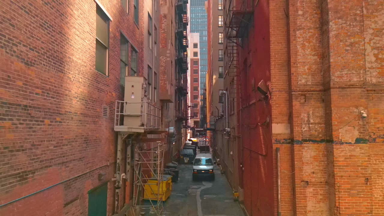 Detroit, USA, 28 July 2025: Flight among the rear facades of the red brick high-rises. Narrow street with rubbish containers and parked cars. Detroit, Michigan, USA