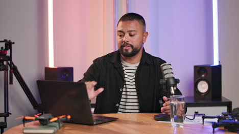 man recording podcast with laptop and microphone