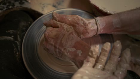 a potter teaches a woman to make clay dishes. a man takes a woman's hands