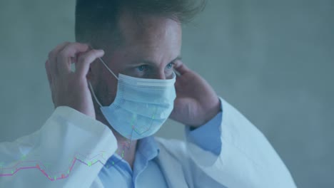 animation of financial data processing over caucasian male doctor wearing face mask at hospital