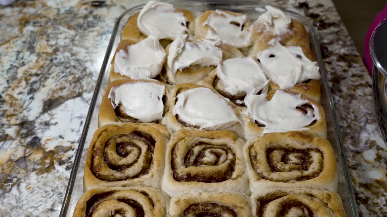 Icing homemade cinnamon rolls with cream cheese frosting