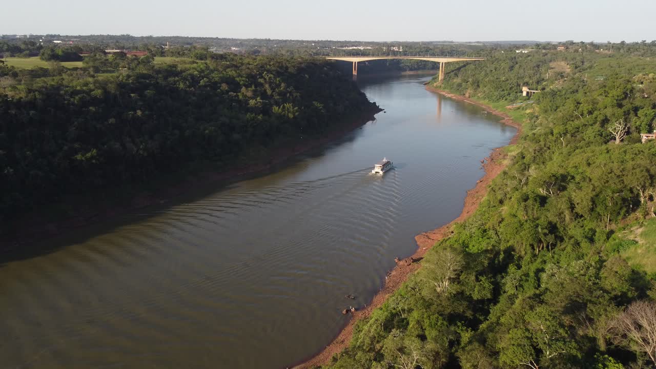 vista aérea de un barco turístico navegando en el río iguazú en la frontera entre argentina y brasil al atardecer