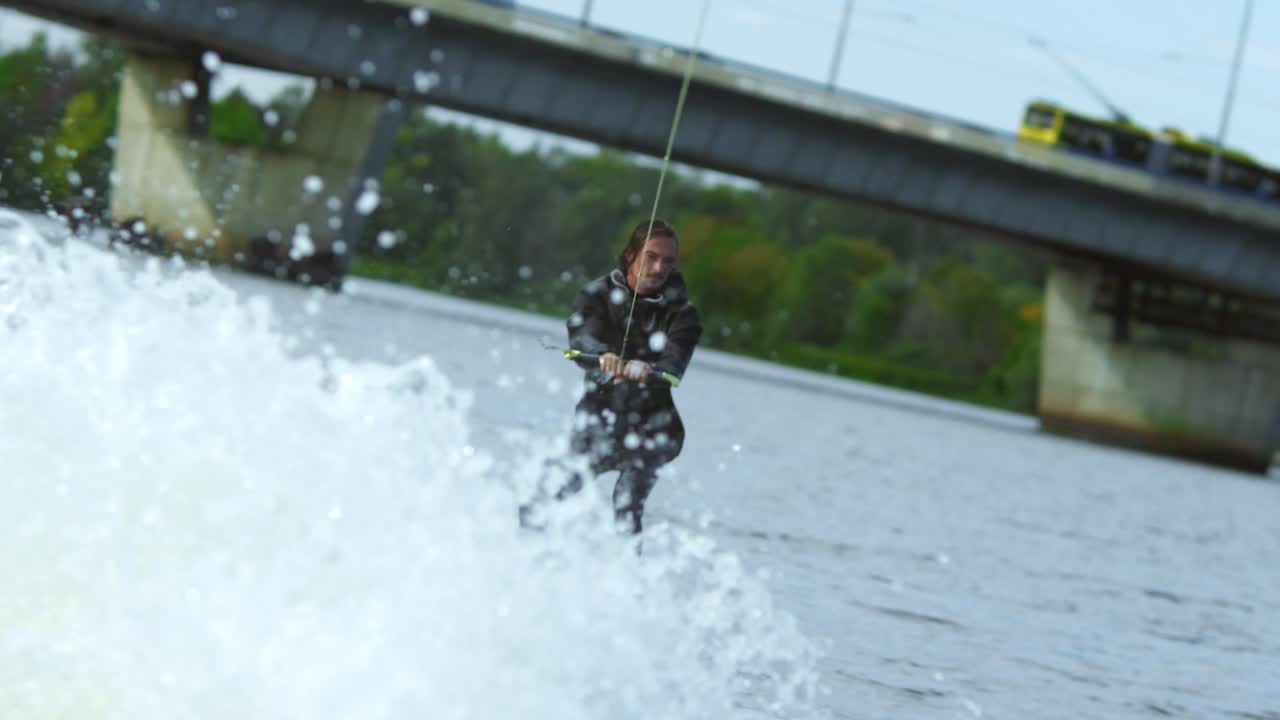 joven montando wakeboard en el río de verano. esquiador de agua moviéndose rápido en salpicaduras