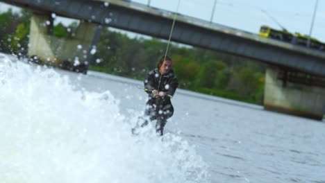 young man riding wakeboard on summer river. waterskier moving fast in splashes