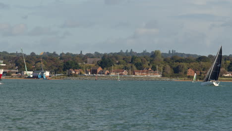 Isle-of-Wight-red-funnel-ferry-goes-through-the-frame-at-the-Solent-Southampton-with-sailboat-and-Weston-in-background