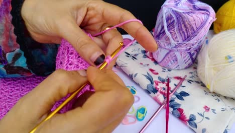 close-up-shot-of-professional-woman-hands-crocheting-dress-for-a-girl-by-hook-and-pink-wool