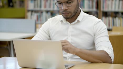 Estudiante-Concentrado-En-Anteojos-Escribiendo-En-La-Computadora-Portátil