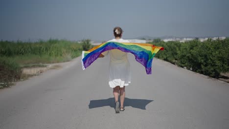 woman walking down a road with a rainbow flag