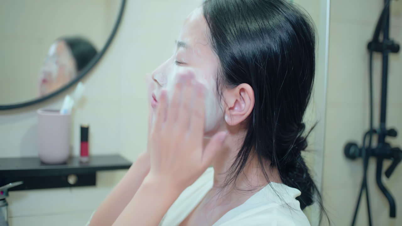 피자마를 입은 아름다운 여성의 피부 관리 피부 관리 얼굴이 건강 관리 제품을 적용하여 깨어나며, 웰니스 신체 관리 및 미용을 위해  바탕에 고립됩니다.