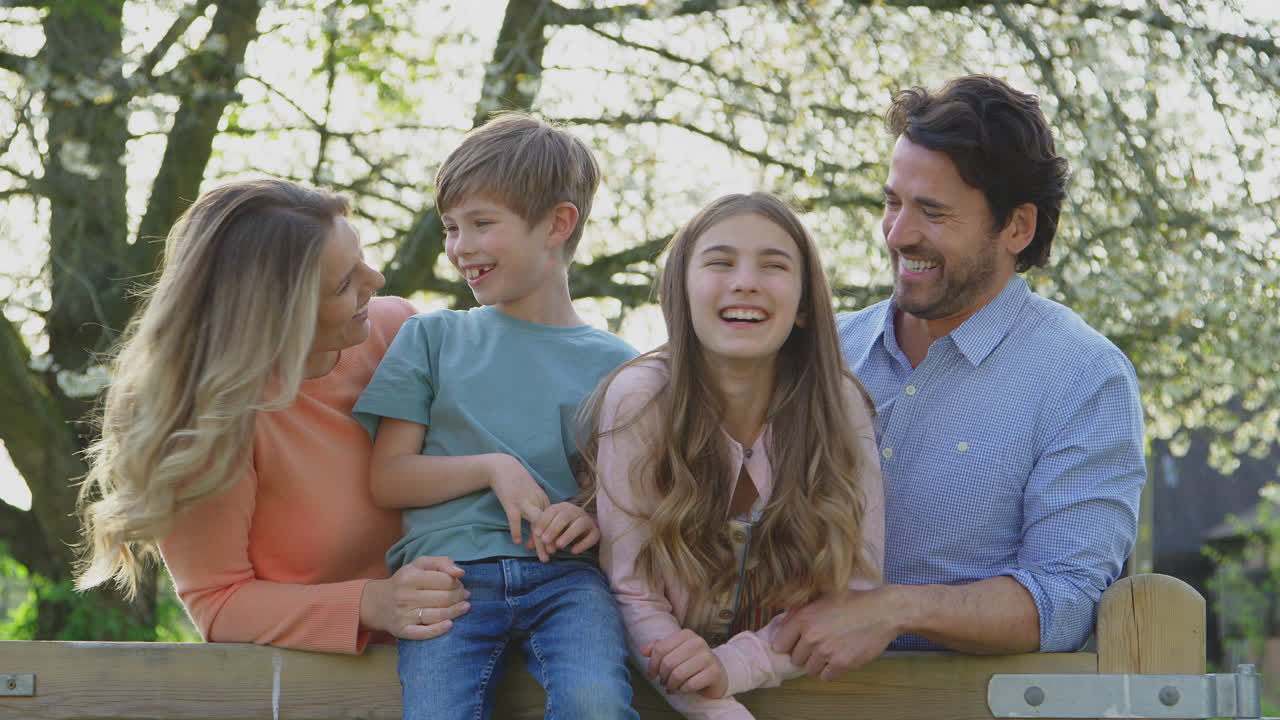 시골 의 나무 울타리 에 앉아 있는 여름 산책 에 있는 가족 의 초상화