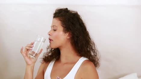 pregnant woman taking a vitamin tablet