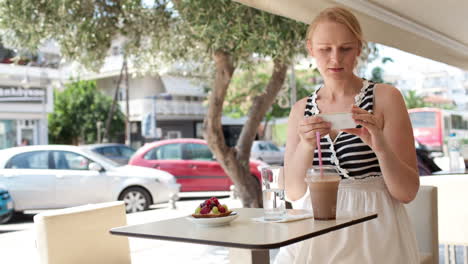 Attractive-woman-taking-picture-of-a-pastry-on-her-mobile