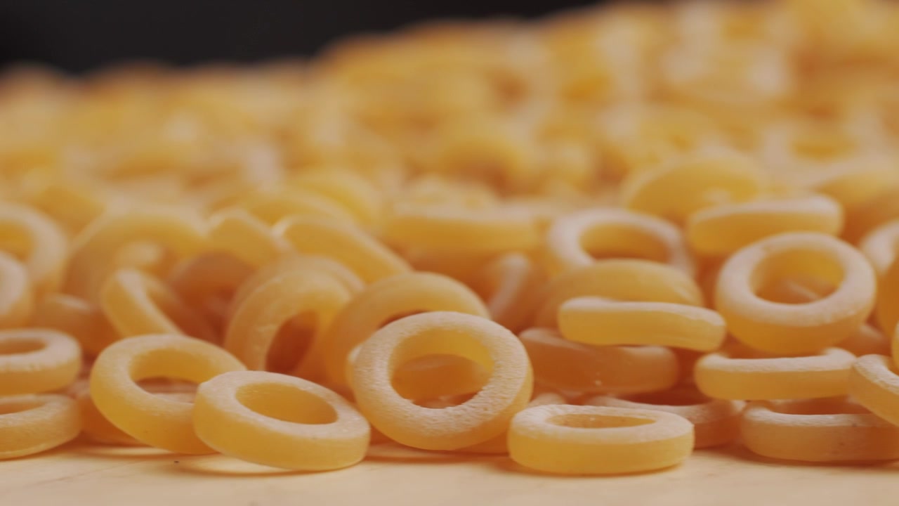 Pasta integrale biologica, maccheroni di semola di grano duro, penne rigate crude in una ciotola di legno. Filmato 4k di alta qualità