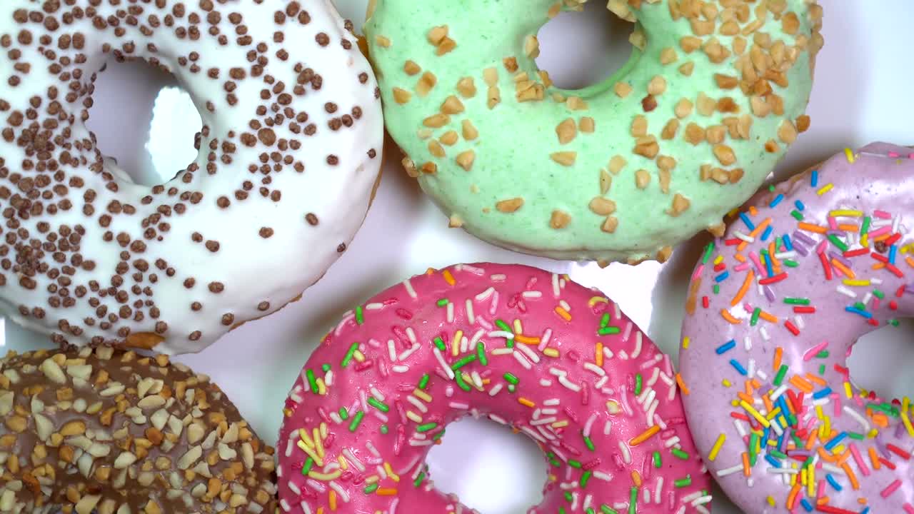 muchas salpicaduras brillantes y coloridas rosquillas, tiro macro, giro rápido en una placa giratoria