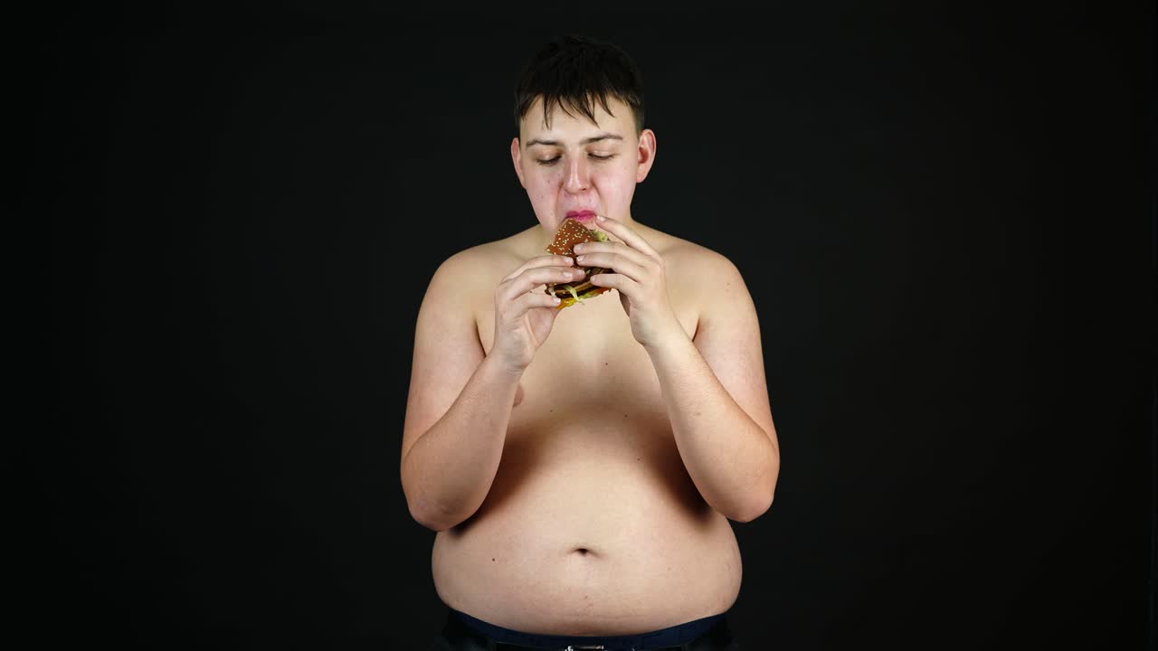 young fat man naked to waist eating junk fast food, overweight in youth and  bad diet concept