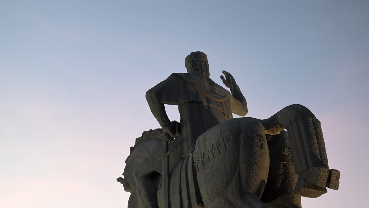 A view looking up behind the King Vakhtang statue, capturing its form and the surrounding landscape in Tbilisi