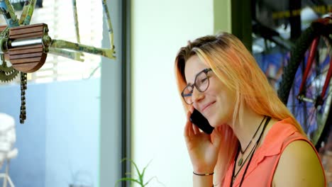 Young-woman-talking-on-the-mobile-phone-in-cafe-4k