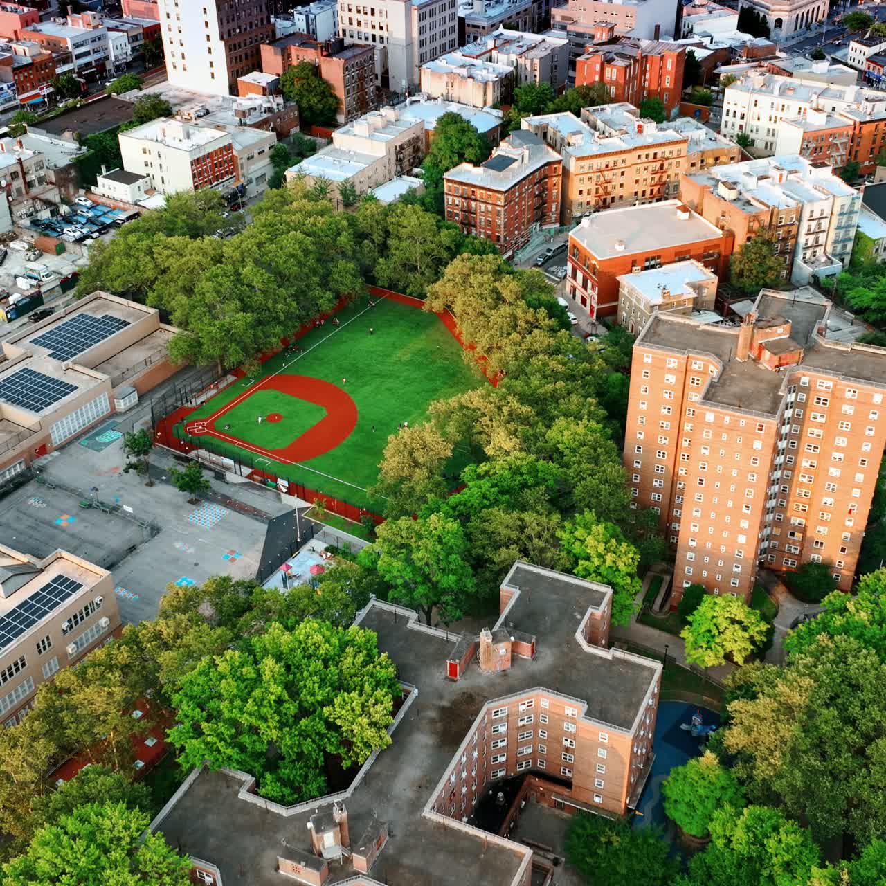 Green residential area with multistoried buildings of unusual design. Stadium for basketball games in the neighborhood. New York panorama. Top view