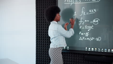 physics teacher explaining equations on blackboard