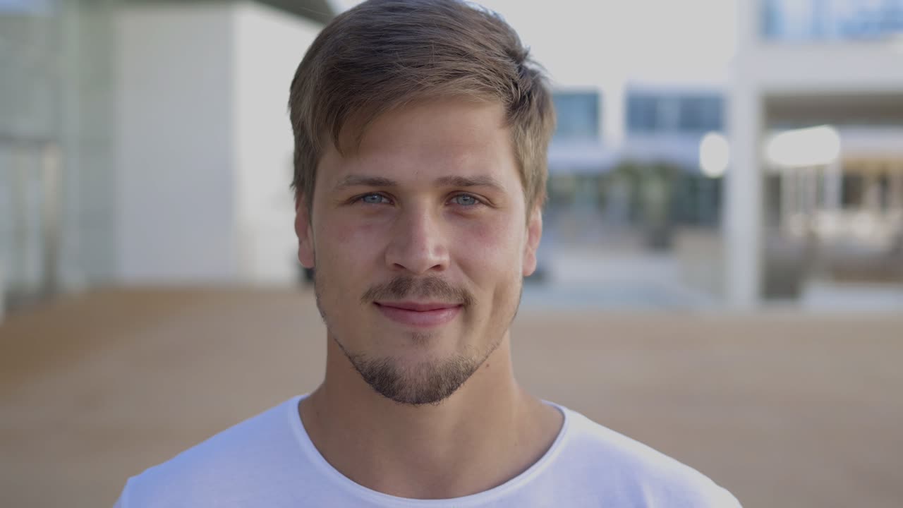 Primo piano di un giovane uomo affascinante e sorridente che guarda in camera