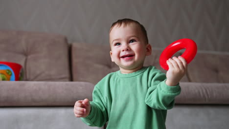 baby playing with a red ring toy