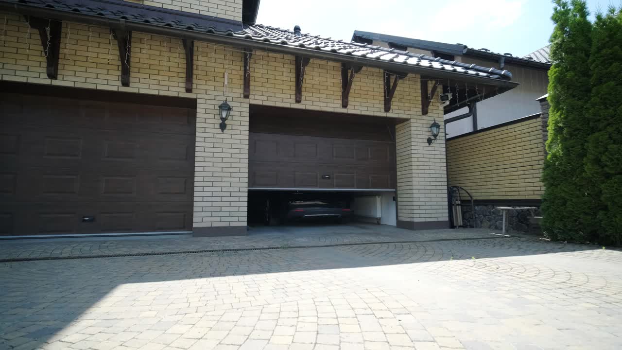 Man driver in car thumbed remote control to open the garage door in the house